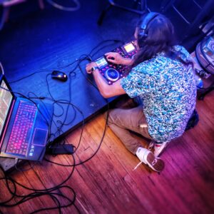 DJ kneeling at stage controlling mixer