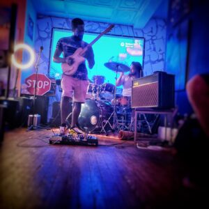 guitarist and drummer performing in front of projector screen