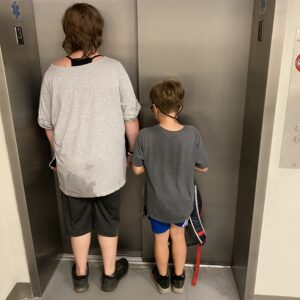 two children standing close to an elevator door